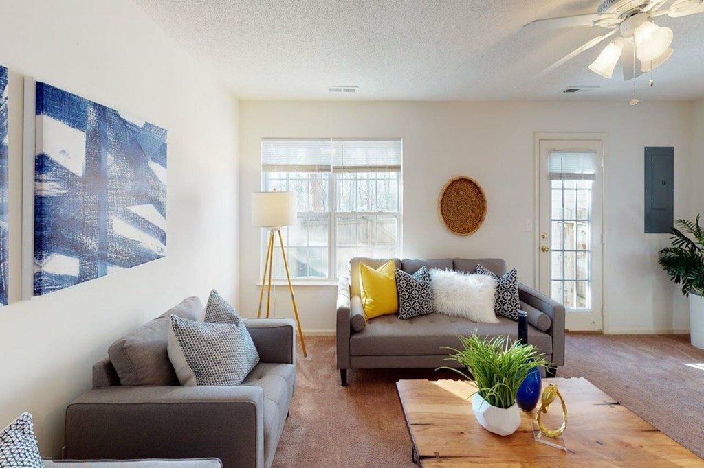 A living room with a grey couch and a blue painting on the wall.