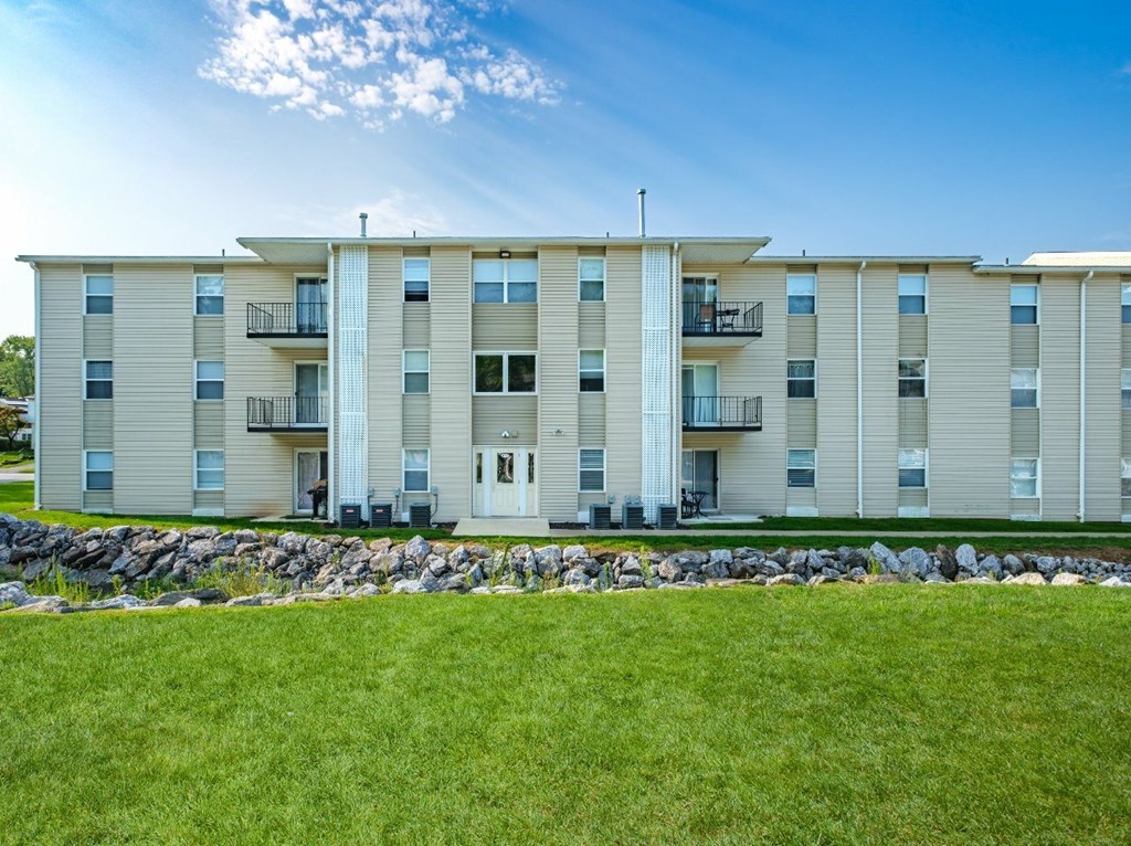 A large apartment building with a grassy area in front.