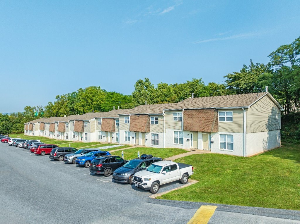 A row of cars parked in front of apartment buildings.
