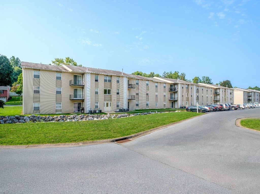 Apartment complex with a parking lot in front.