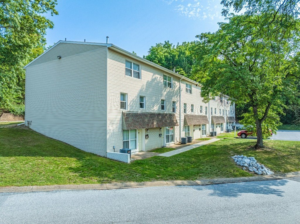 A two-story house with a white exterior and a red car parked in the driveway.
