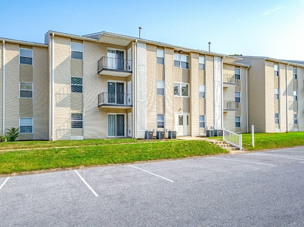 Apartment building with a parking lot in front.