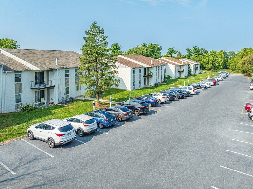 A parking lot with cars parked in front of apartment buildings.