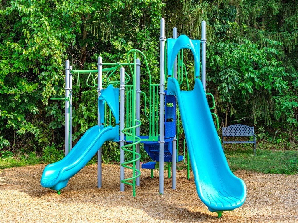 A blue and green playground slide in a park.