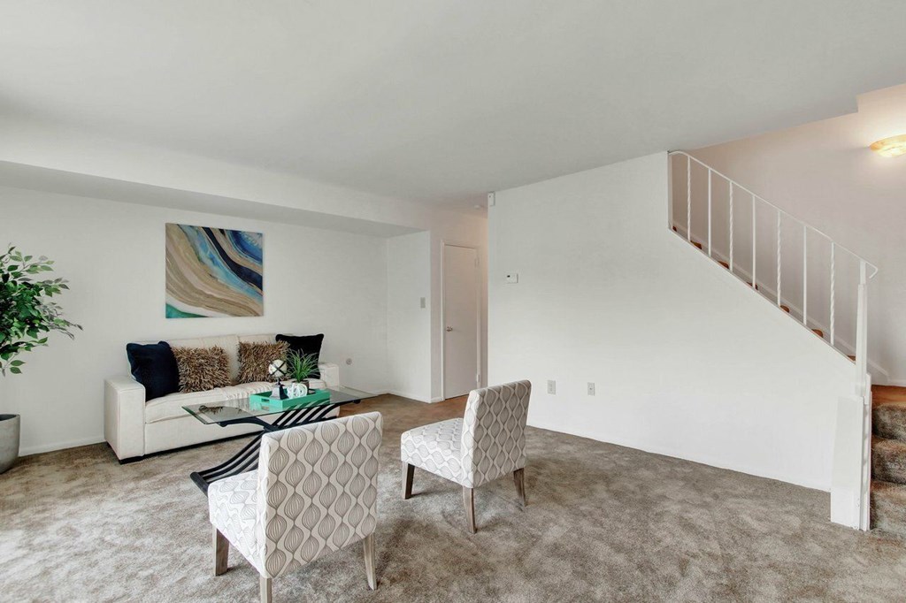 A living room with a white couch and a painting on the wall.