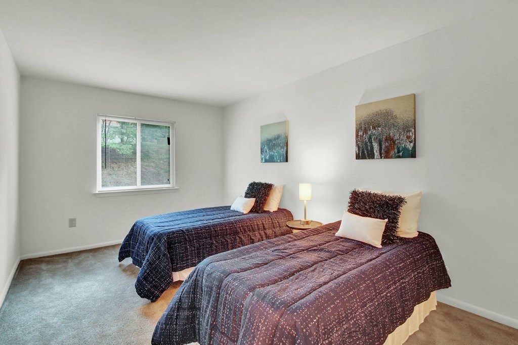 A bedroom with two beds and a window.