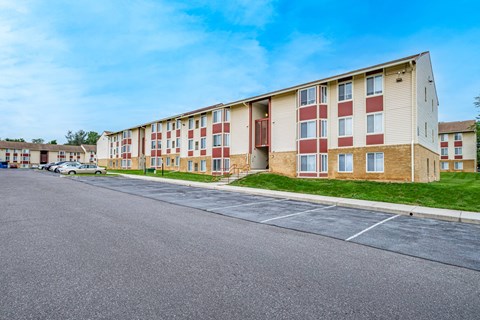 A long building with a parking lot in front.