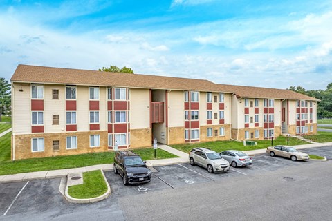 A parking lot in front of a building with cars parked.