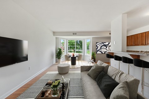 A living room with a grey couch and a black television on the wall.