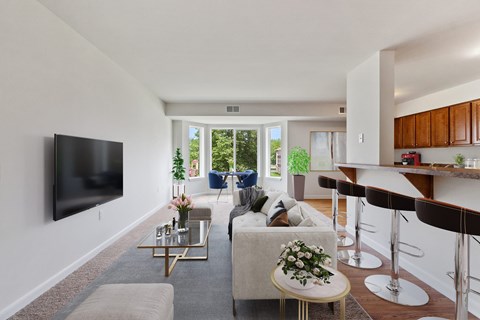 A living room with a white couch and a flat screen TV mounted on the wall.