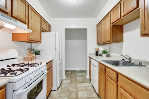 A kitchen with white appliances and wooden cabinets.