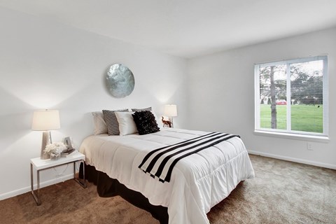 A bedroom with a bed, two lamps, and a round decoration on the wall.