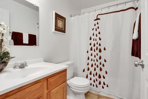 A white bathroom with a brown shower curtain.