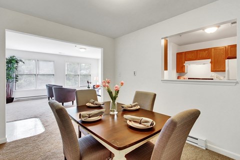 A dining room with a table set for two and a potted plant.