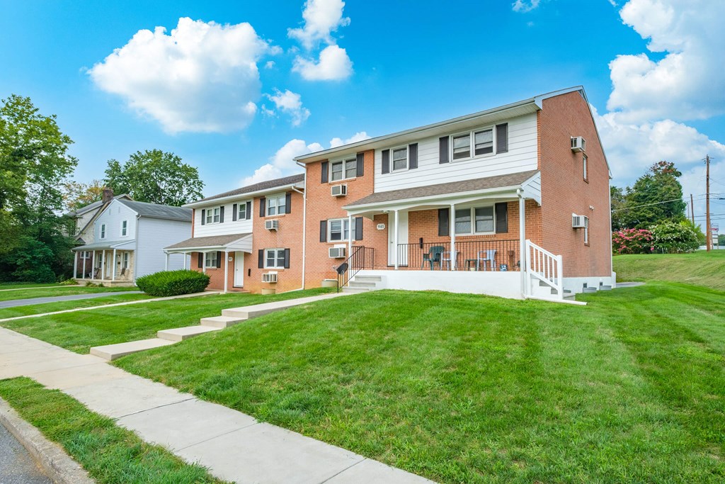 A red brick apartment building with a white front porch.