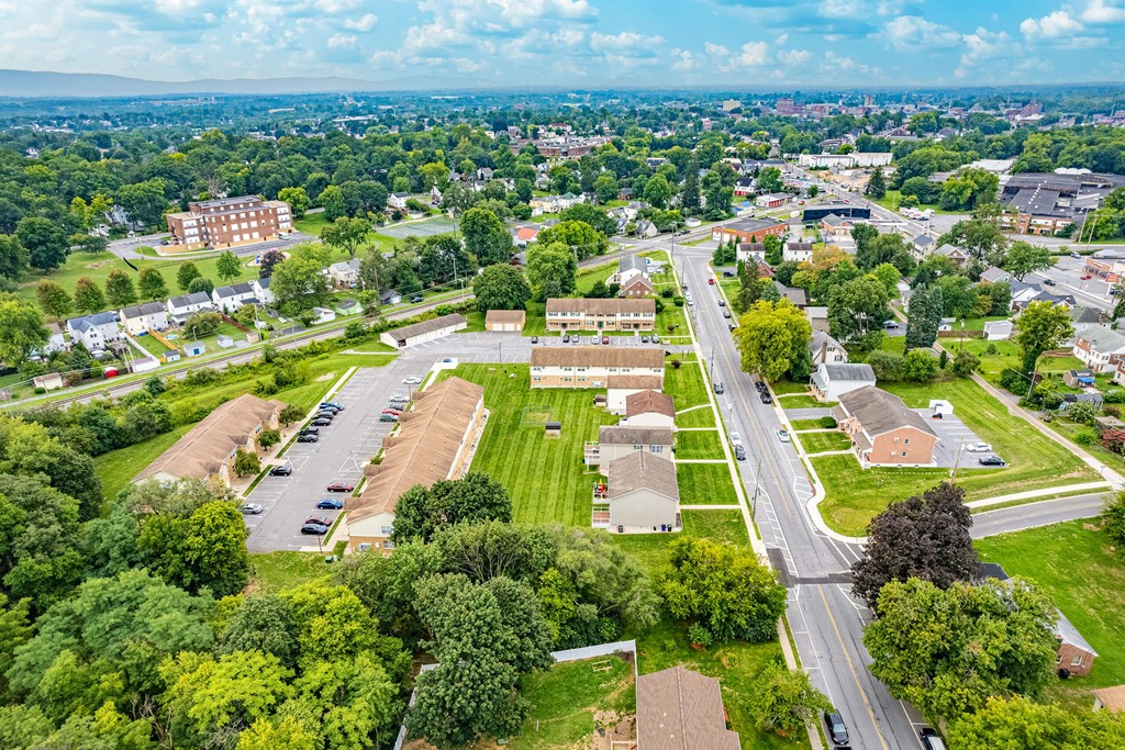 A bird's eye view of a residential area with houses, trees, and a parking lot.