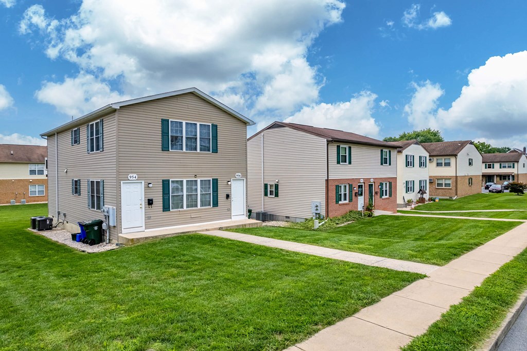 A row of houses with green lawns and a blue sky.