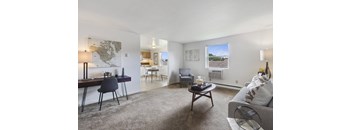 A living room with a grey couch, a coffee table, and a dining table with chairs.