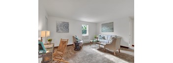 A living room with a white couch, a wooden chair, a glass table, and a painting on the wall.