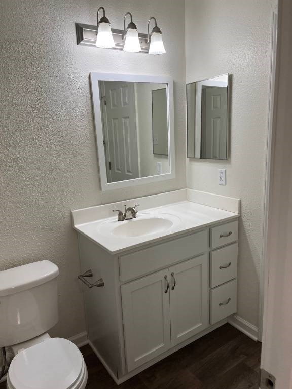 A white bathroom with a toilet, sink, and mirror.