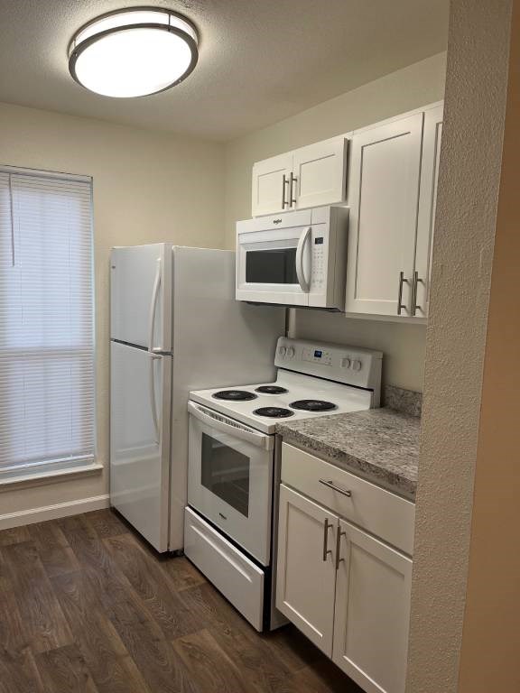 A kitchen with white appliances and wooden floors.