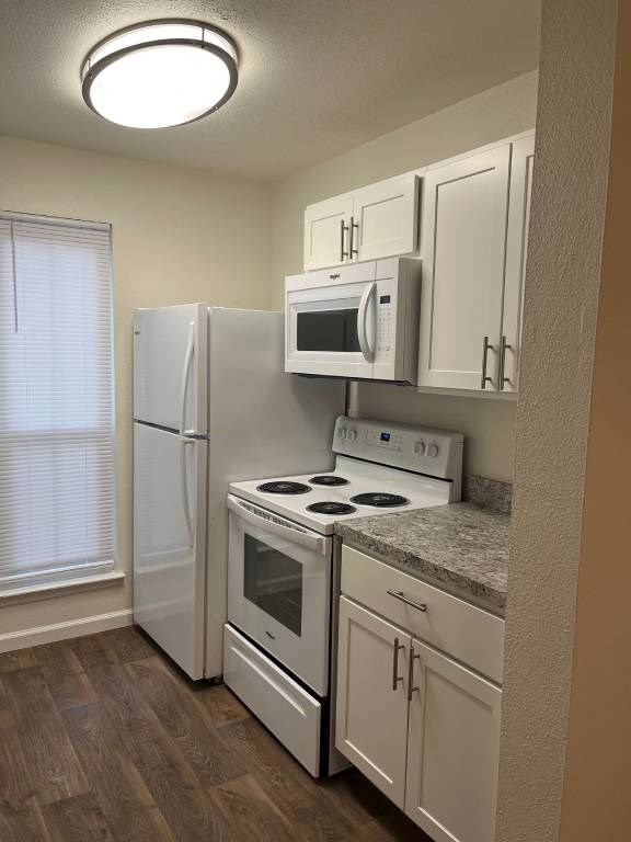 A kitchen with white appliances and wooden floors.