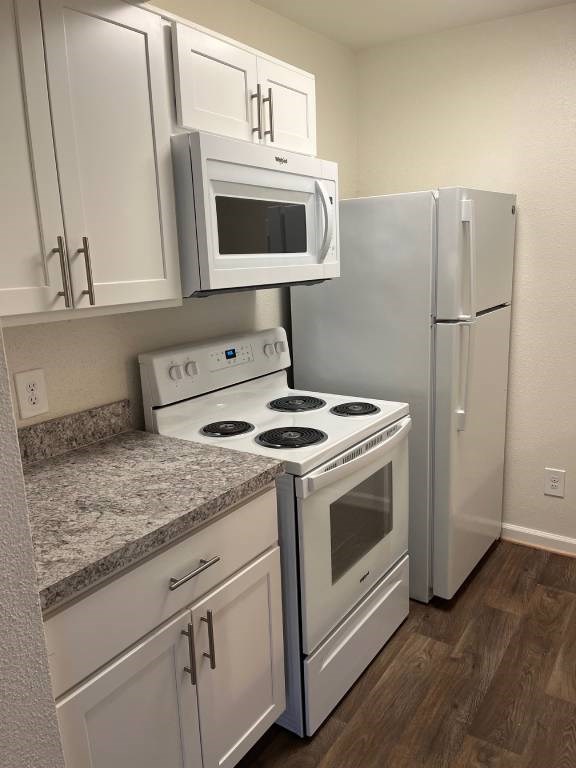 A kitchen with a white stove top oven, microwave, and refrigerator.