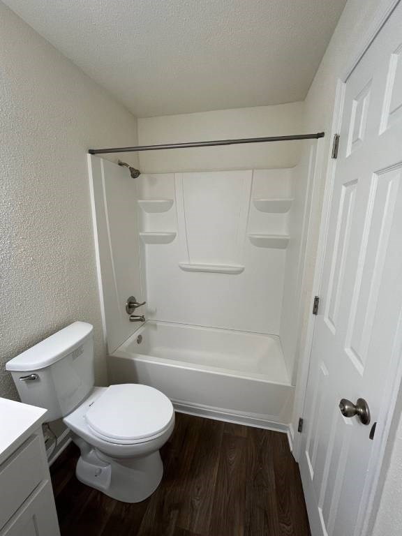 A white toilet sits next to a white bathtub in a small bathroom.