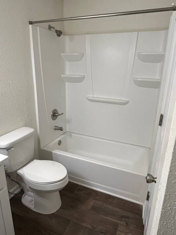 A white toilet and bathtub in a small bathroom.