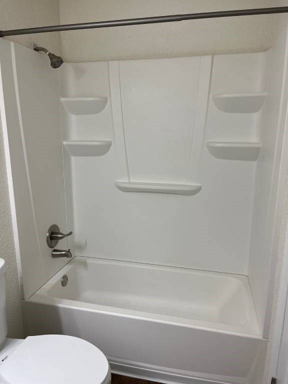 A white bathroom with a toilet and a walk in shower.