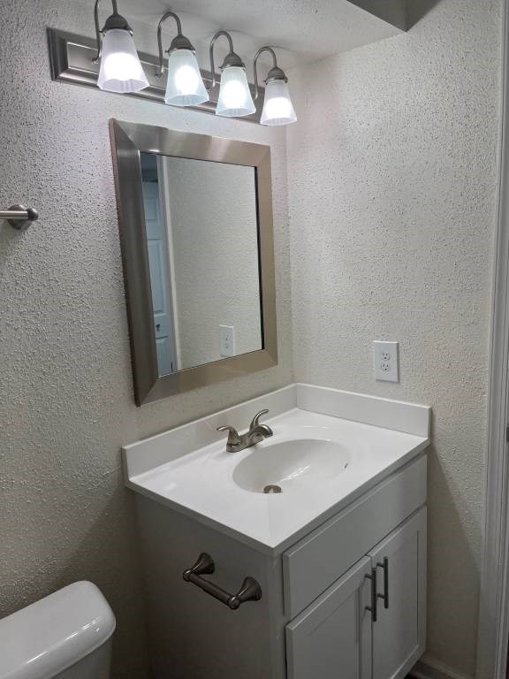 A bathroom with a sink, mirror and lights.