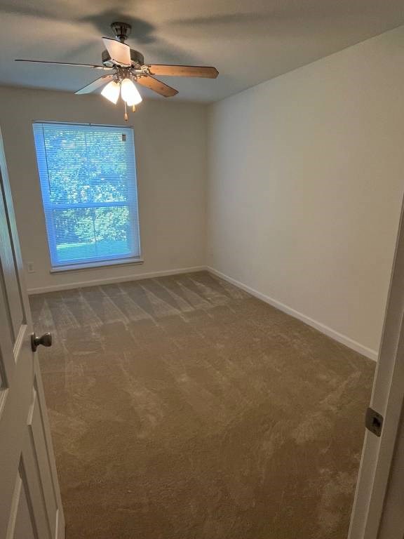 A room with a ceiling fan and a window with a view of trees.