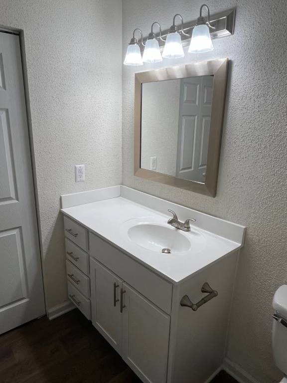 A bathroom with a white sink and a mirror with lights above it.