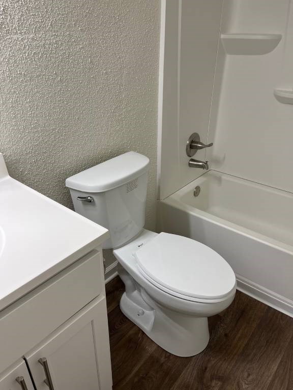 A white toilet in a small bathroom with a white sink.