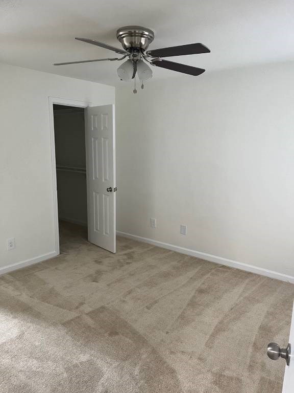 A room with a ceiling fan and carpeted floor.