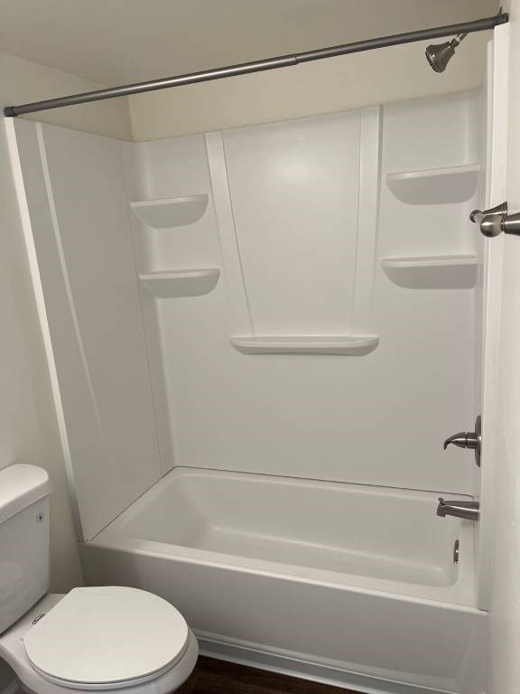 A white toilet sits next to a white bathtub in a small bathroom.