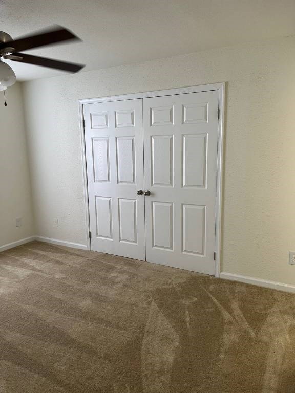 A room with a white door and a ceiling fan.
