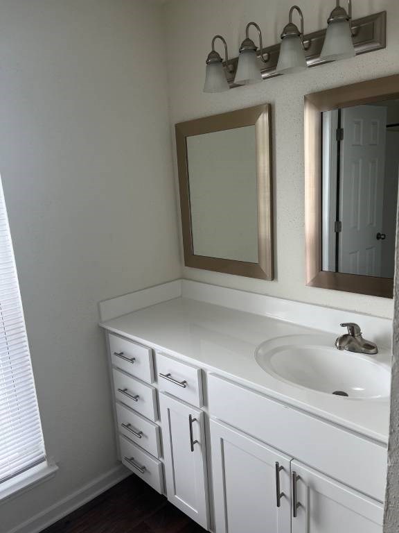 A white bathroom vanity with a sink and mirror.