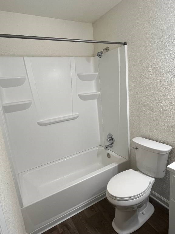 A white toilet sits next to a white bathtub in a small bathroom.