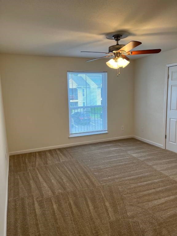 A room with a ceiling fan and carpeted floor.