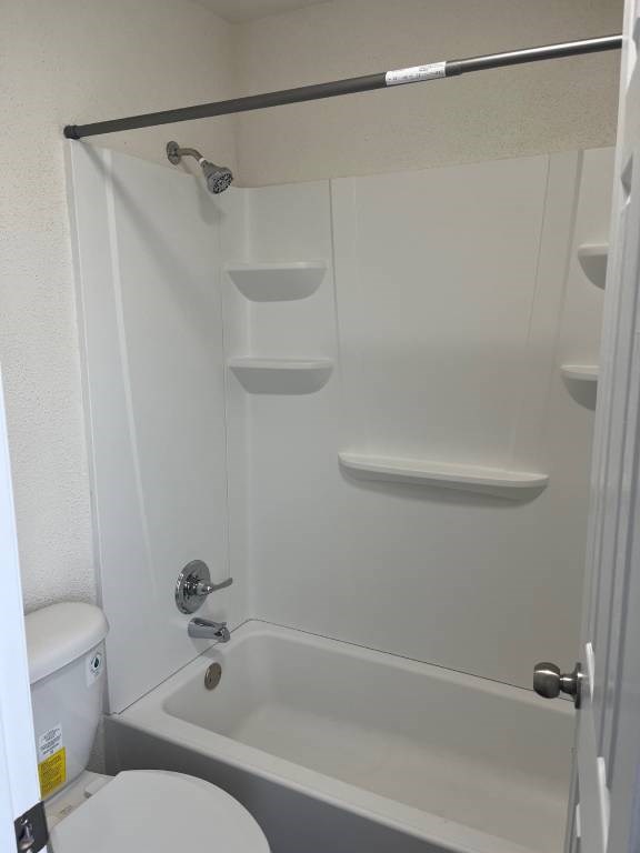 A white bathroom with a toilet, tub, and shelves.
