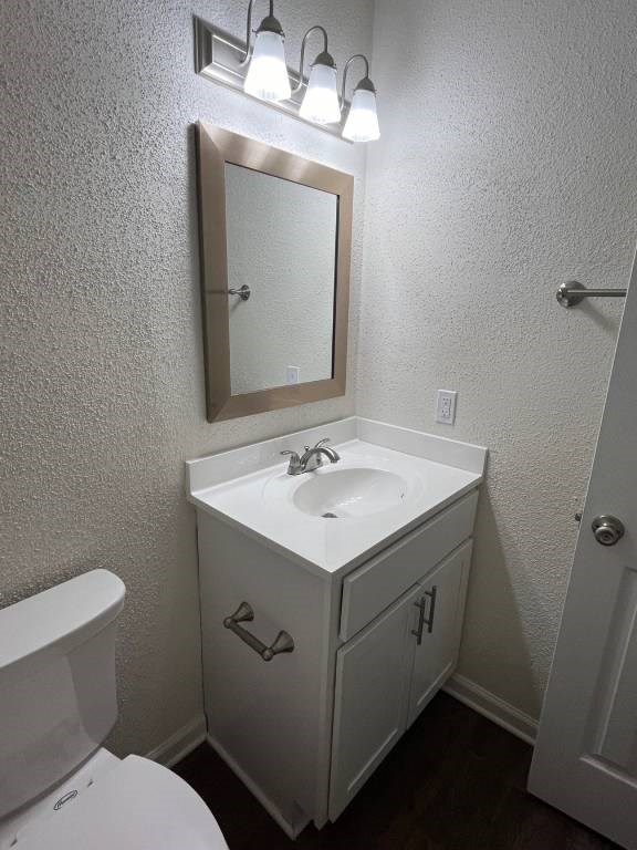 A white bathroom with a toilet, sink and mirror.