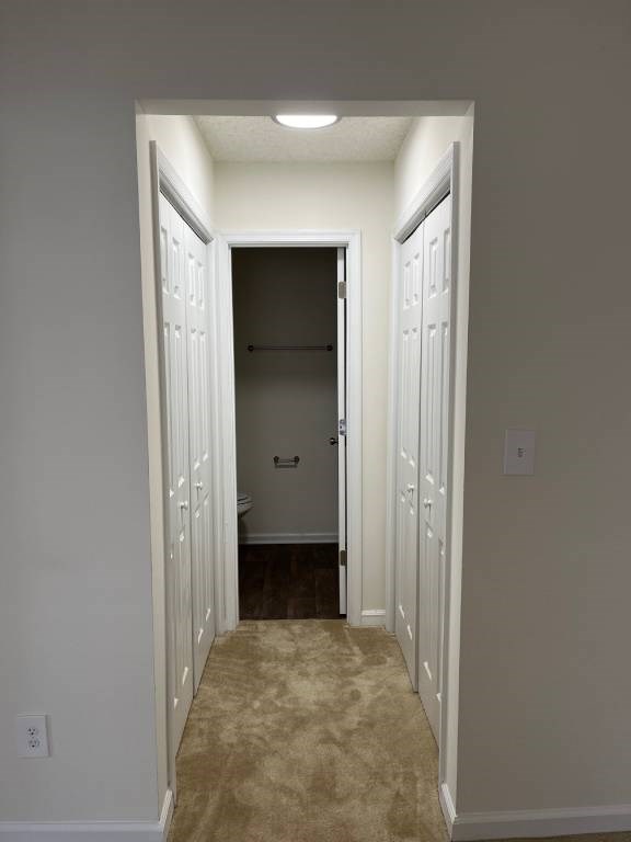 A hallway with white walls and a carpeted floor.