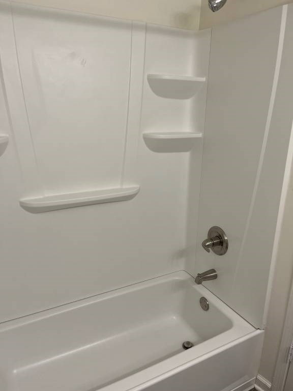 A white bathroom with a tub and shelves.