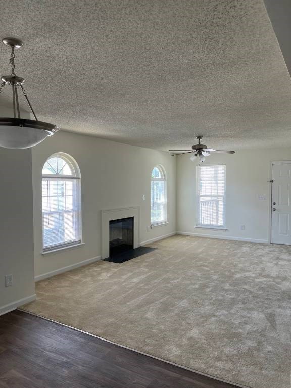 A spacious living room with a fireplace and a ceiling fan.