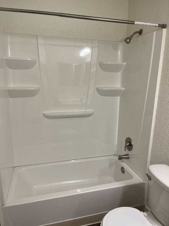 A white bathroom with a glass shower door and a toilet.