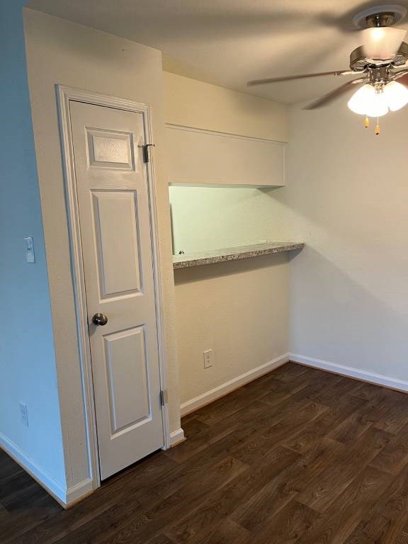 A room with a white door and a ceiling fan.