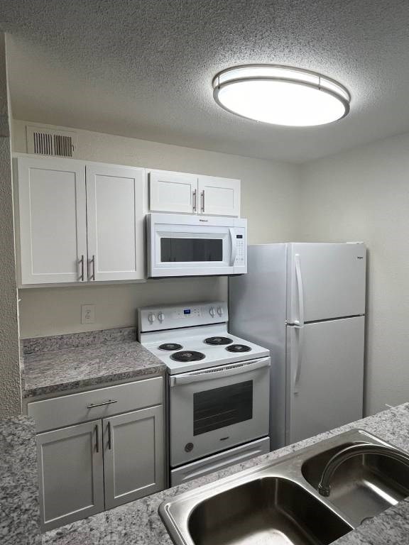 A kitchen with a stove, oven, microwave, and refrigerator.