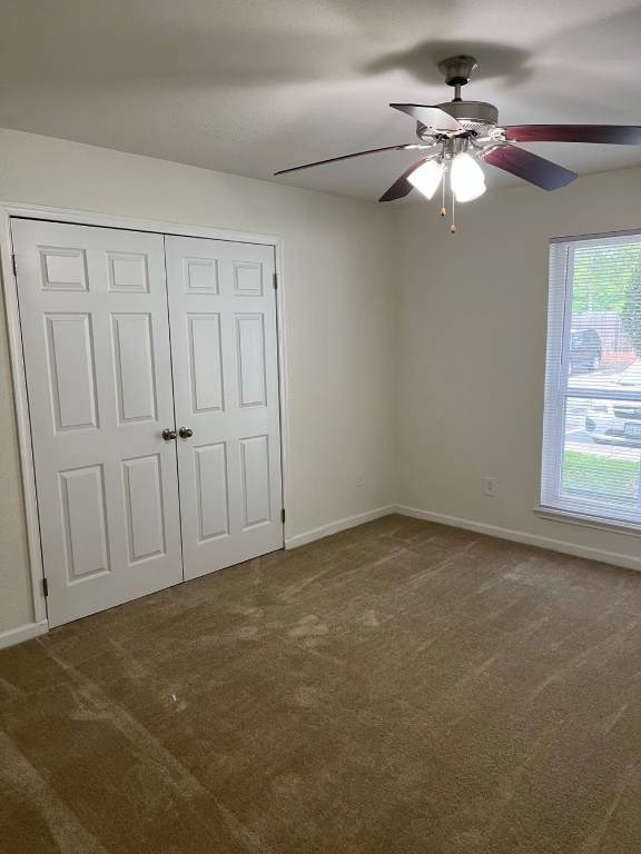 A room with a ceiling fan and a window with a view of a street.