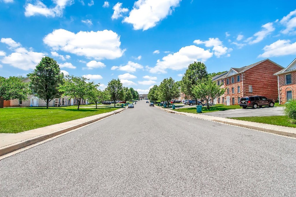 A street view with cars parked on the side and houses on both sides.
